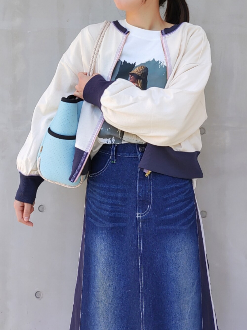 ブルー系のトートバッグ、ブルー系のデニムスカート、ホワイト系のスニーカーを着用したレディースの冬コーディネートの5枚目の写真