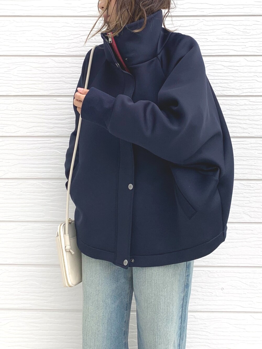 ブルー系のデニムパンツ、ホワイト系のショルダーバッグ、ブルー系のブルゾンを着用したレディースの冬コーディネートの3枚目の写真