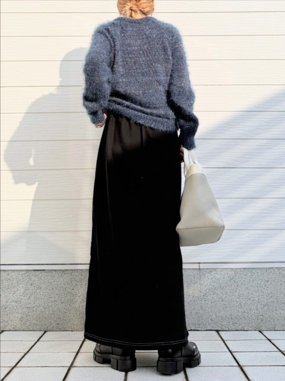 グレー系のトートバッグ、ブラック系のブーツ、グレー系のスカートを着用したレディースの秋コーディネートの3枚目の写真