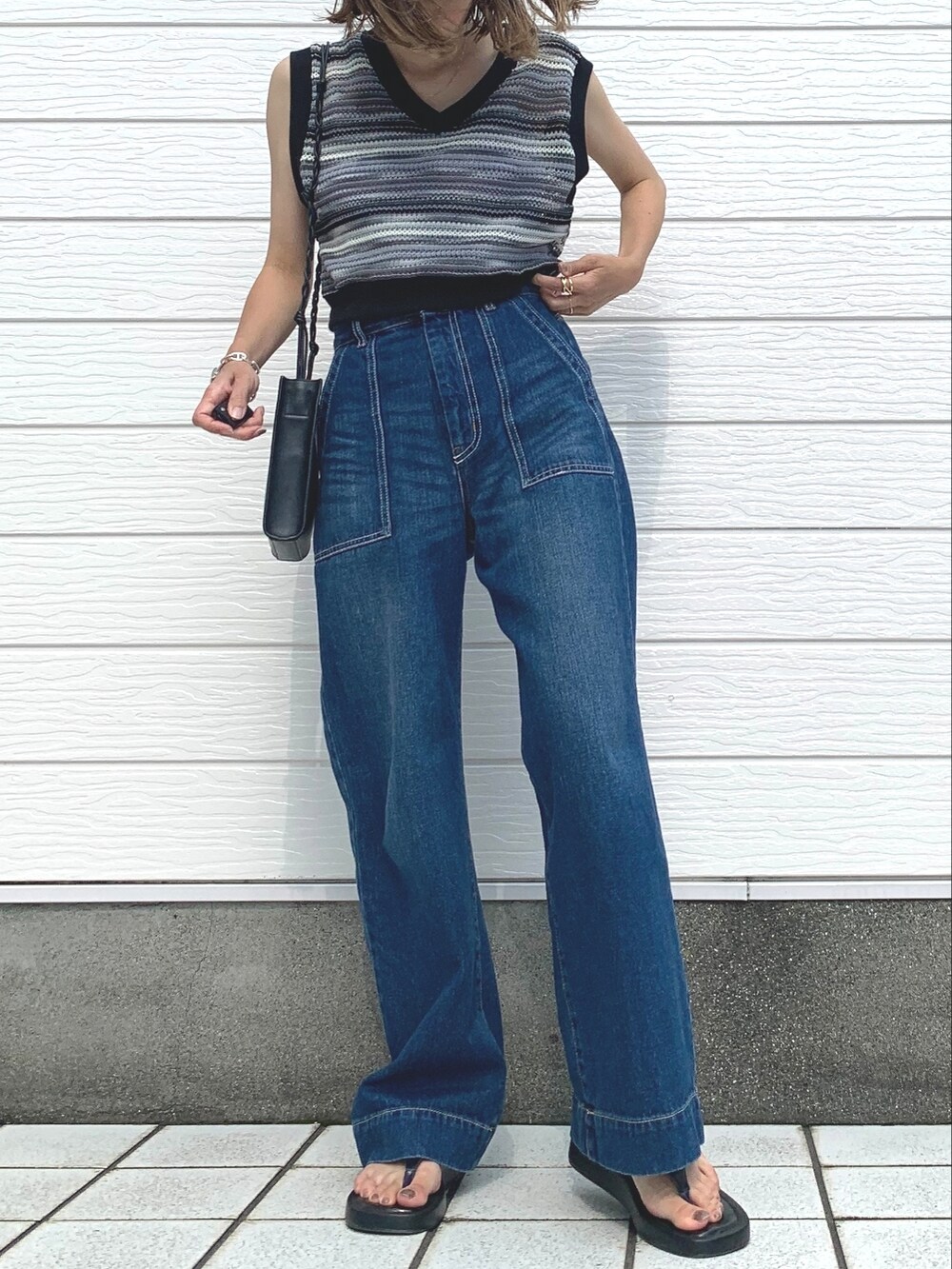 ブルー系のデニムパンツ、ホワイト系のキャミソール、ブラック系のベストを着用したレディースの夏コーディネートの2枚目の写真
