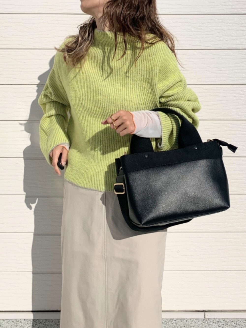 グレー系のニット/セーター、ホワイト系のスカート、ブラック系のトートバッグを着用したレディースの秋コーディネートの3枚目の写真