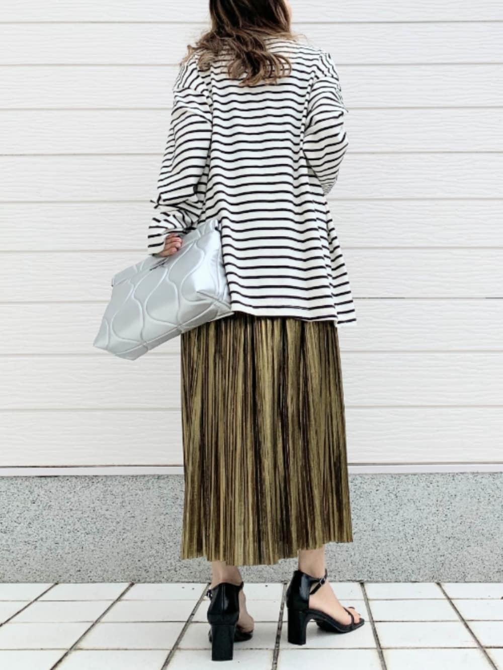 ホワイト系のTシャツ/カットソー、シルバー系のクラッチバッグ、ゴールド系のスカートを着用したレディースの春コーディネートの3枚目の写真