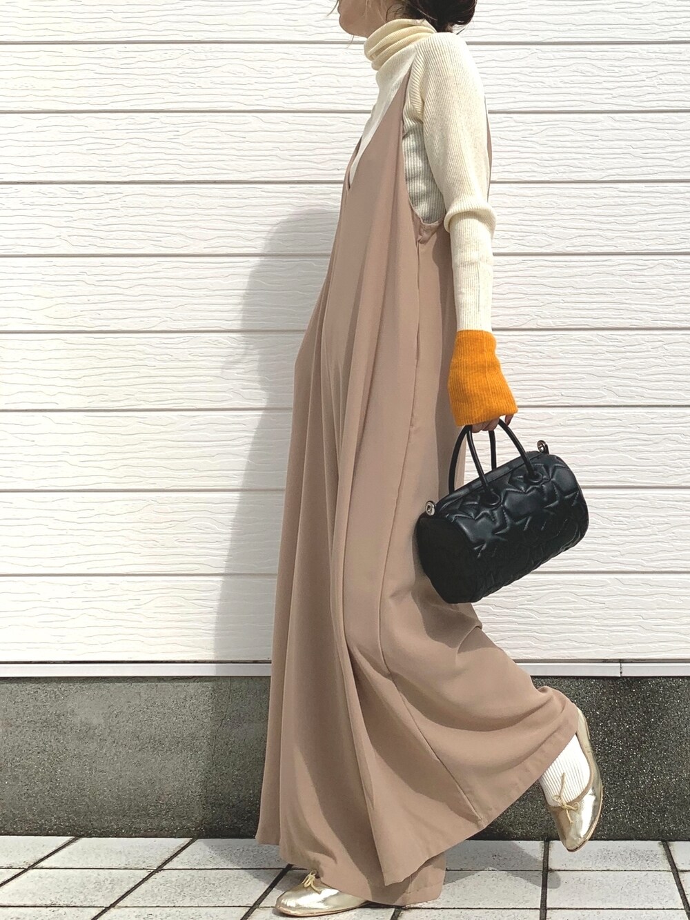 ホワイト系のニット/セーター、ベージュ系のサロペット/オーバーオール、ブラック系のドラムバッグを着用したレディースの秋コーディネートの2枚目の写真