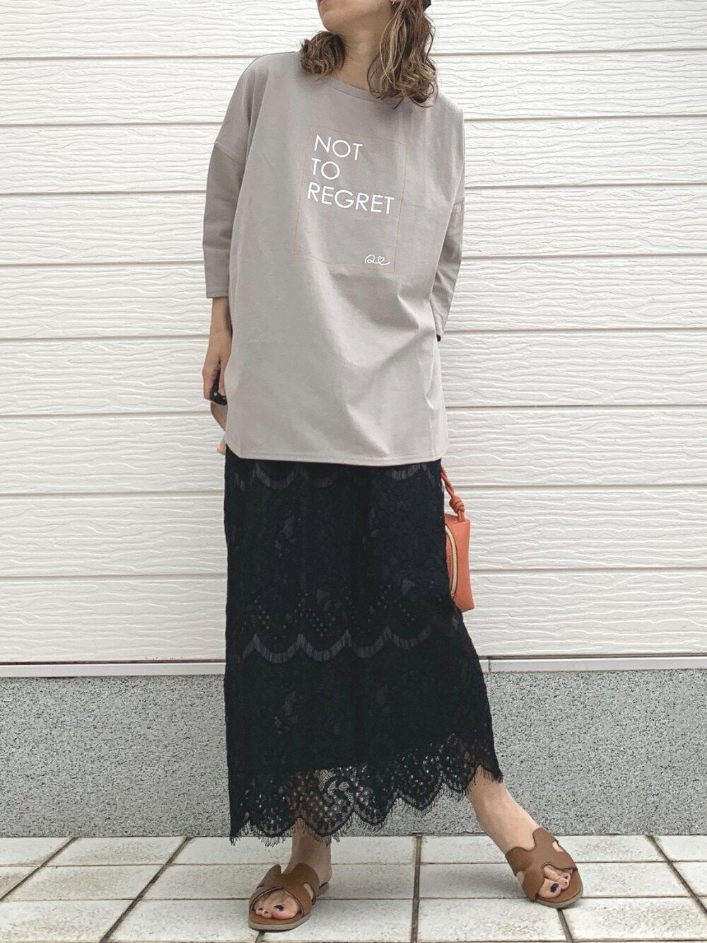 オレンジ系のハンドバッグ、ベージュ系のTシャツ/カットソー、ブラック系のスカートを着用したレディースの春コーディネートの2枚目の写真