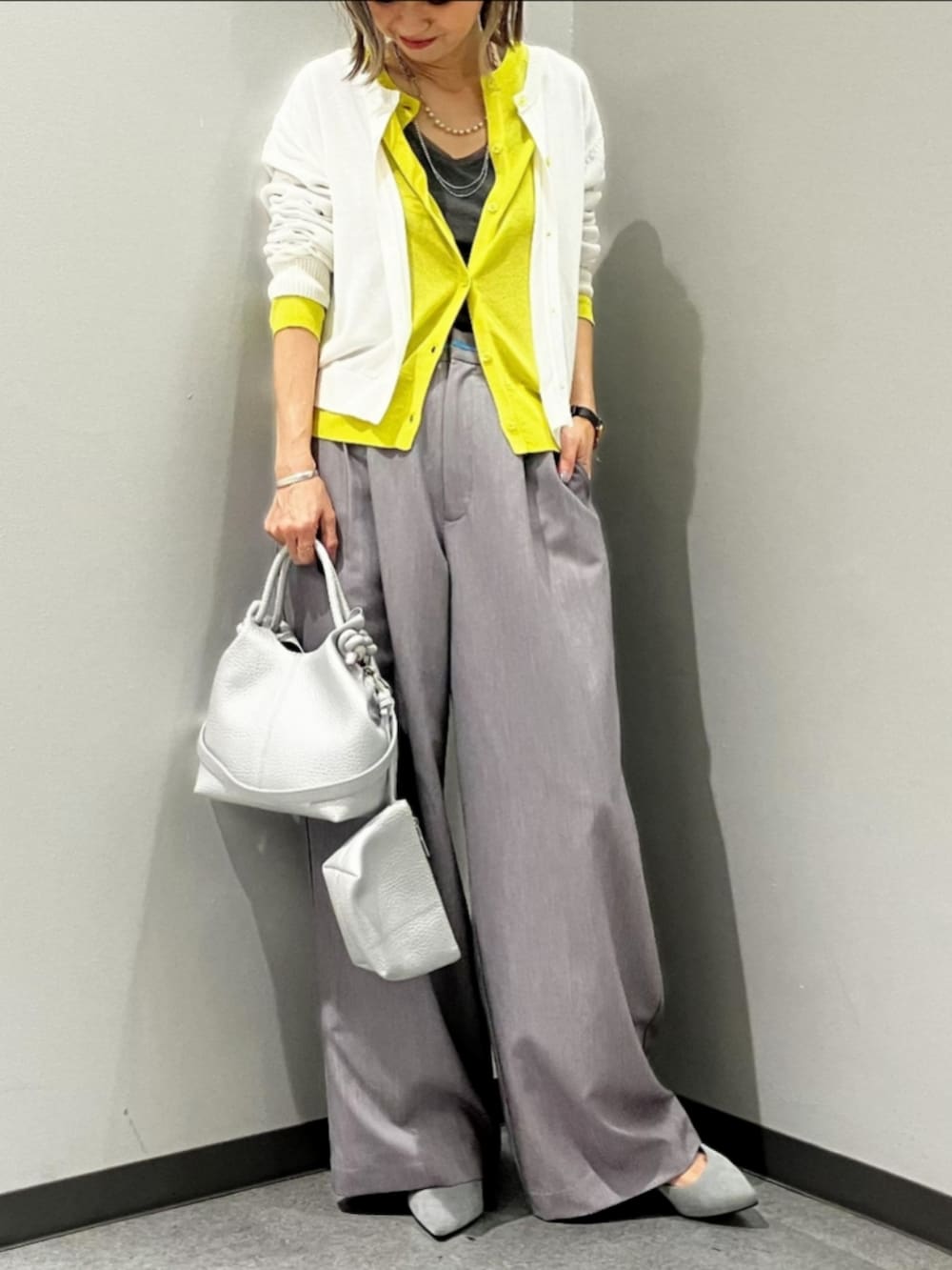 グレー系のスラックス、ホワイト系のTシャツ/カットソー、ホワイト系のカーディガン/ボレロを着用したレディースの春コーディネートの2枚目の写真