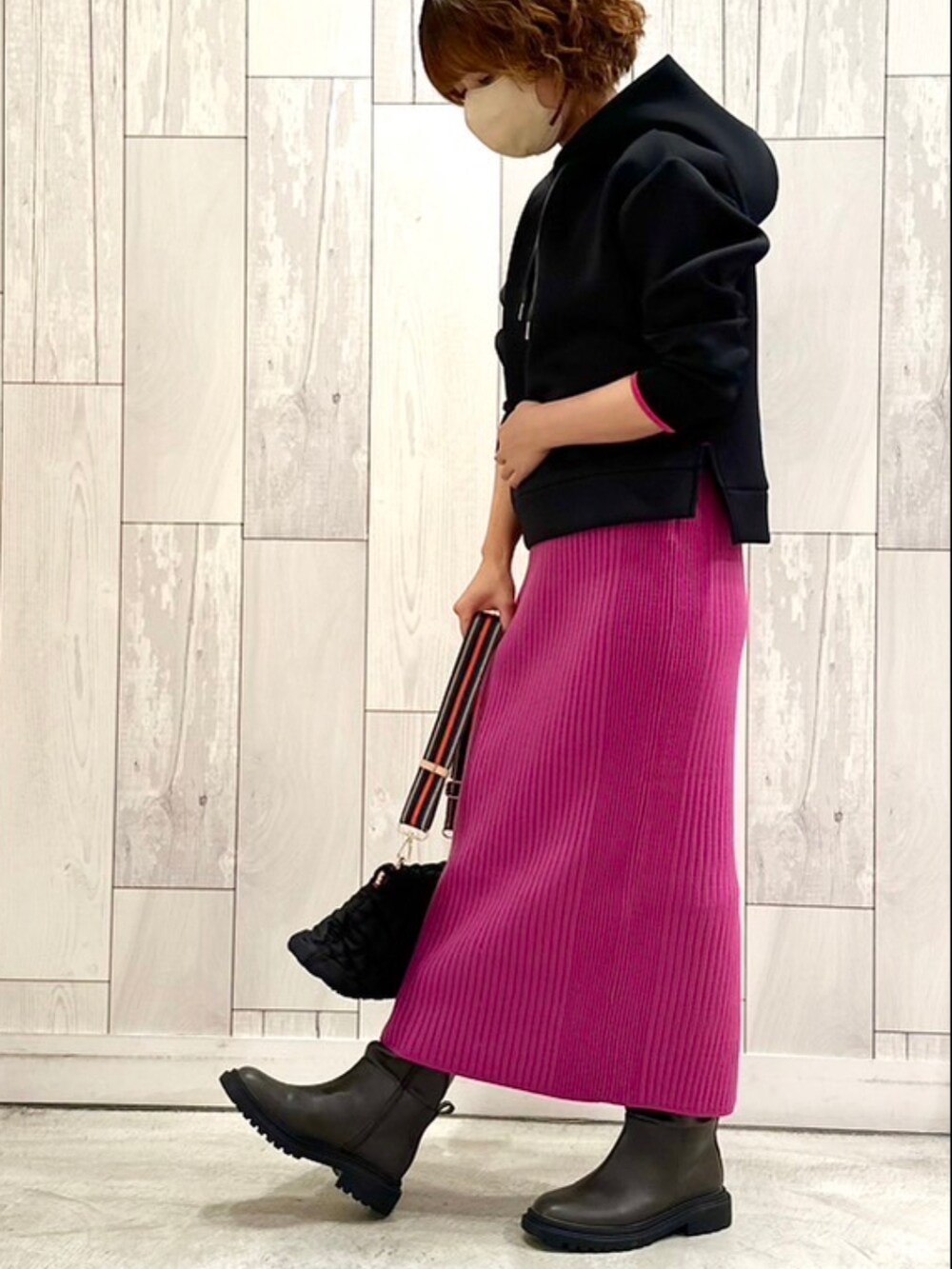 ブラック系のショルダーバッグ、ピンク系のスカート、ブラック系のパーカーを着用したレディースの秋コーディネートの2枚目の写真