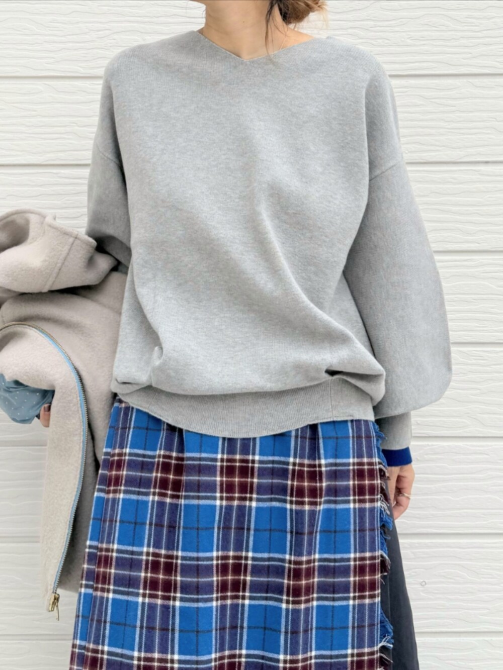 ブルー系のスカート、ブラック系のブーツ、ベージュ系のその他アウターを着用したレディースの秋コーディネートの4枚目の写真