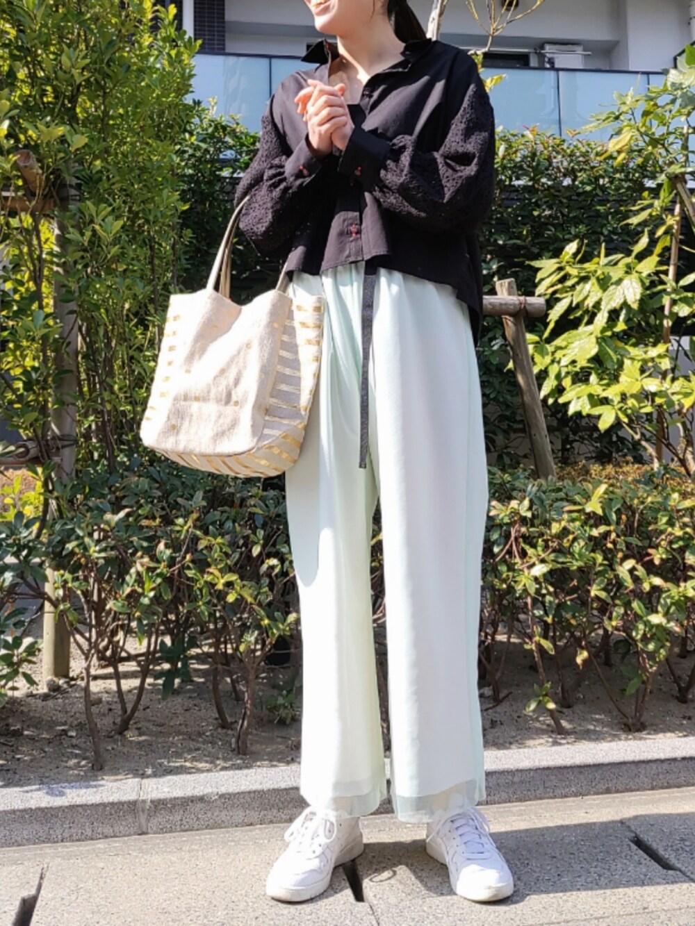 ゴールド系のトートバッグ、ベージュ系のその他パンツ、ホワイト系のスニーカーを着用したレディースの春コーディネートの2枚目の写真