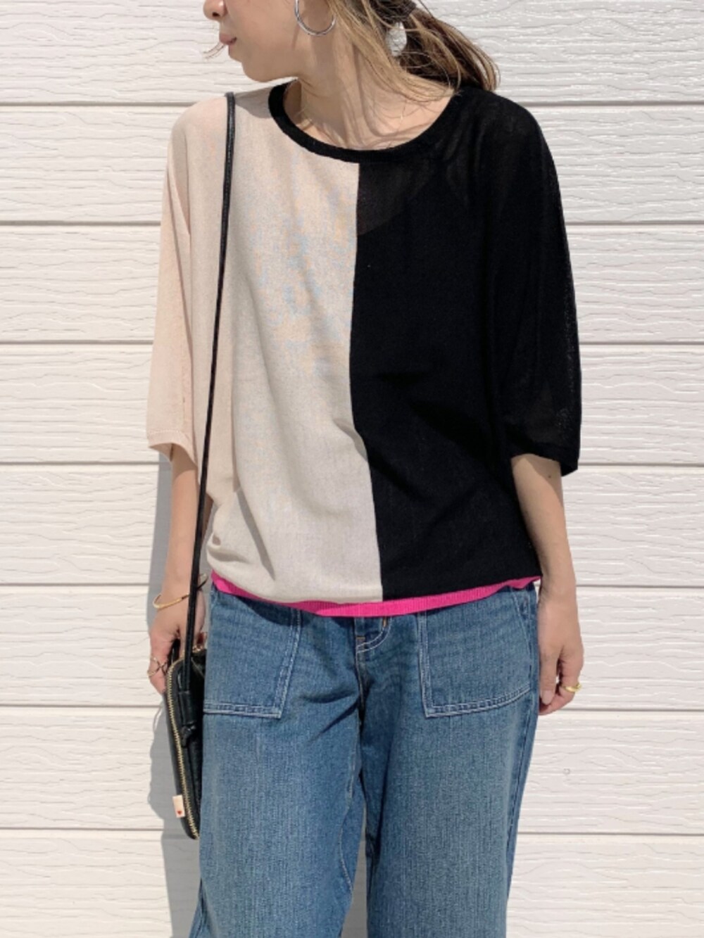 ブルー系のデニムパンツ、ブラック系のショルダーバッグ、ブラック系のニット/セーターを着用したレディースの春コーディネートの3枚目の写真