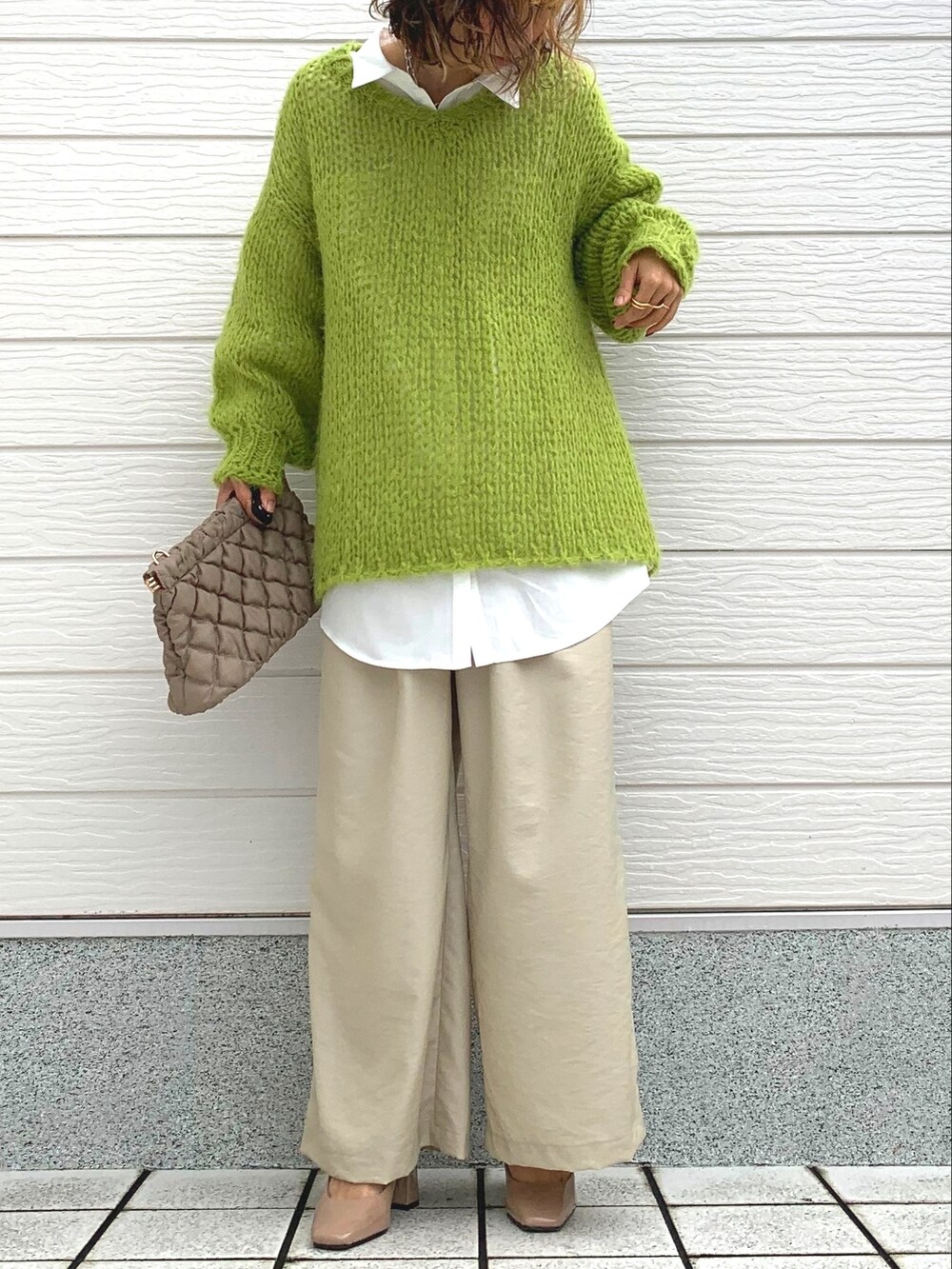 グリーン系のニット/セーター、ホワイト系のシャツ/ブラウス、ベージュ系のショルダーバッグを着用したレディースの冬コーディネートの2枚目の写真