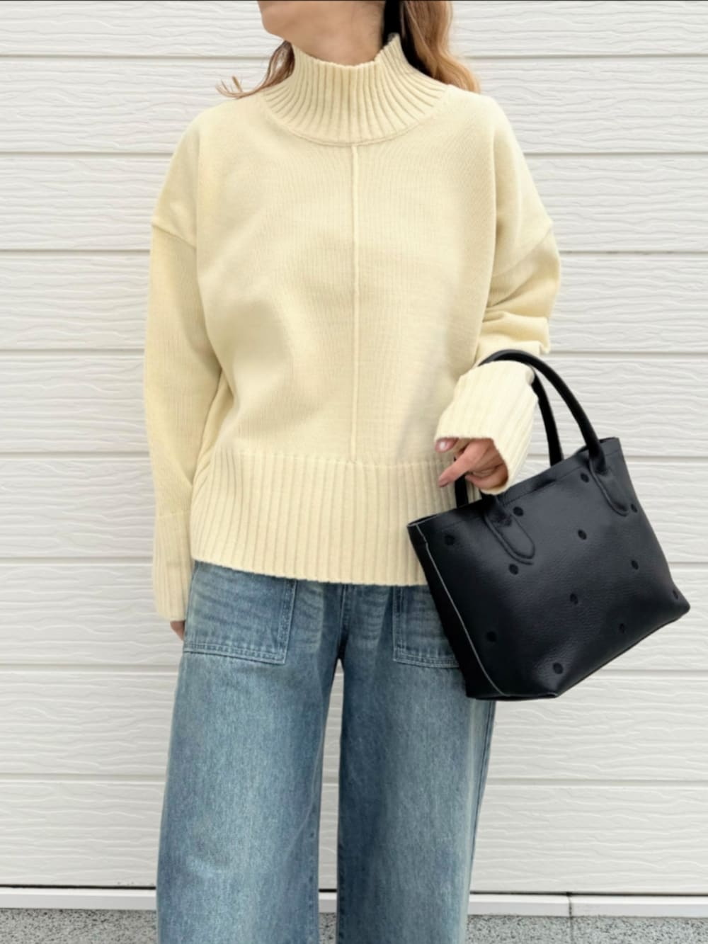 ブルー系のデニムパンツ、ブラック系のトートバッグ、ホワイト系のニット/セーターを着用したレディースの冬コーディネートの3枚目の写真