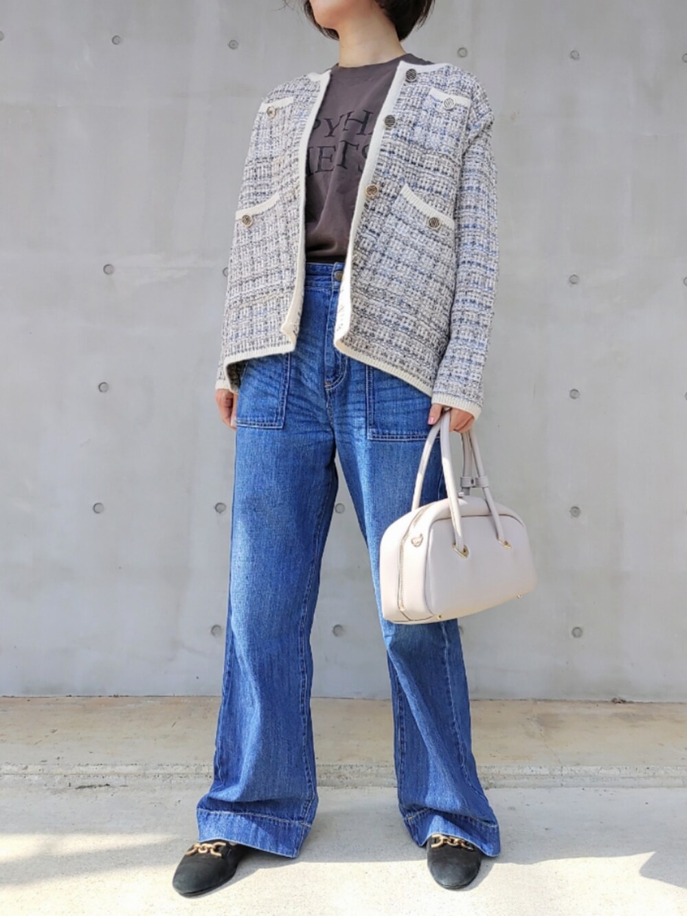 ホワイト系のボストンバッグ、ブルー系のデニムパンツ、ホワイト系のカーディガン/ボレロを着用したレディースの秋コーディネートの2枚目の写真