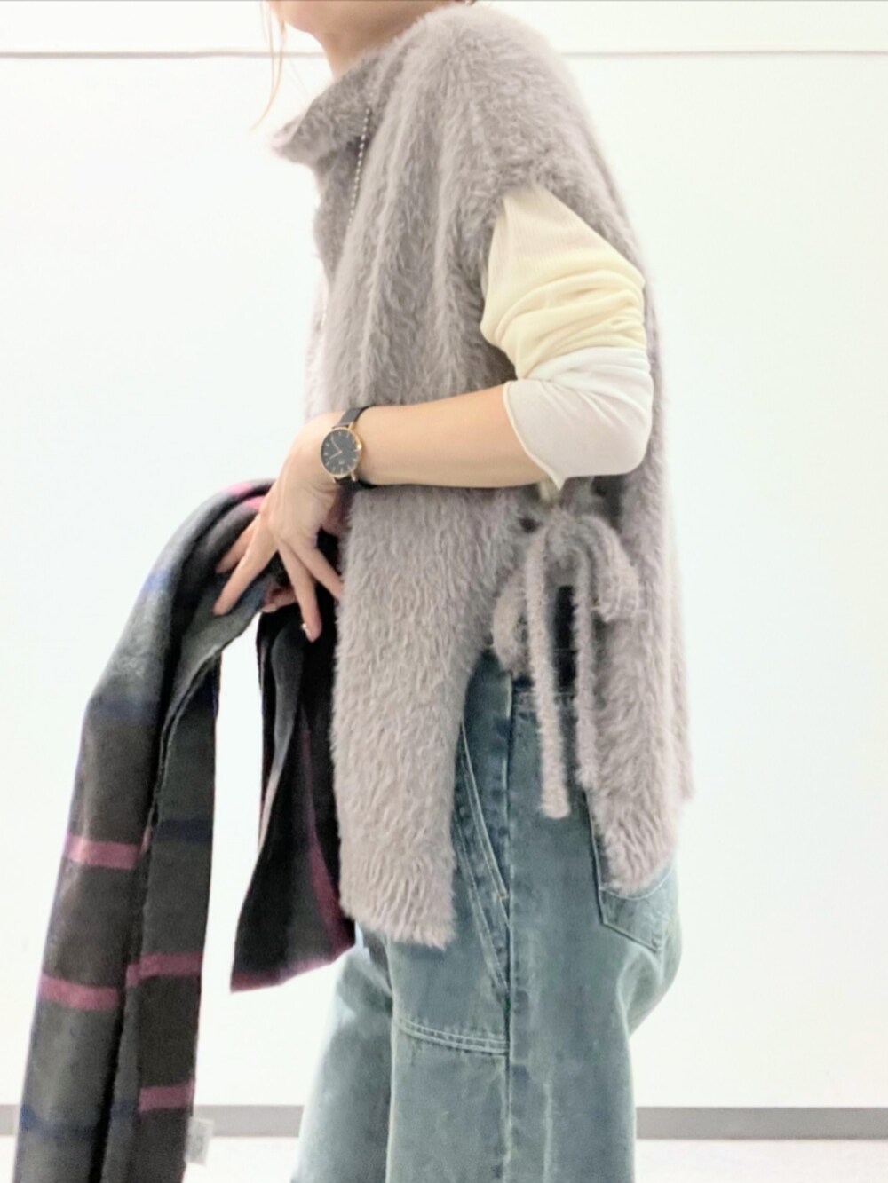ブルー系のデニムパンツ、グレー系のベスト、ベージュ系のTシャツ/カットソーを着用したレディースの秋コーディネートの5枚目の写真