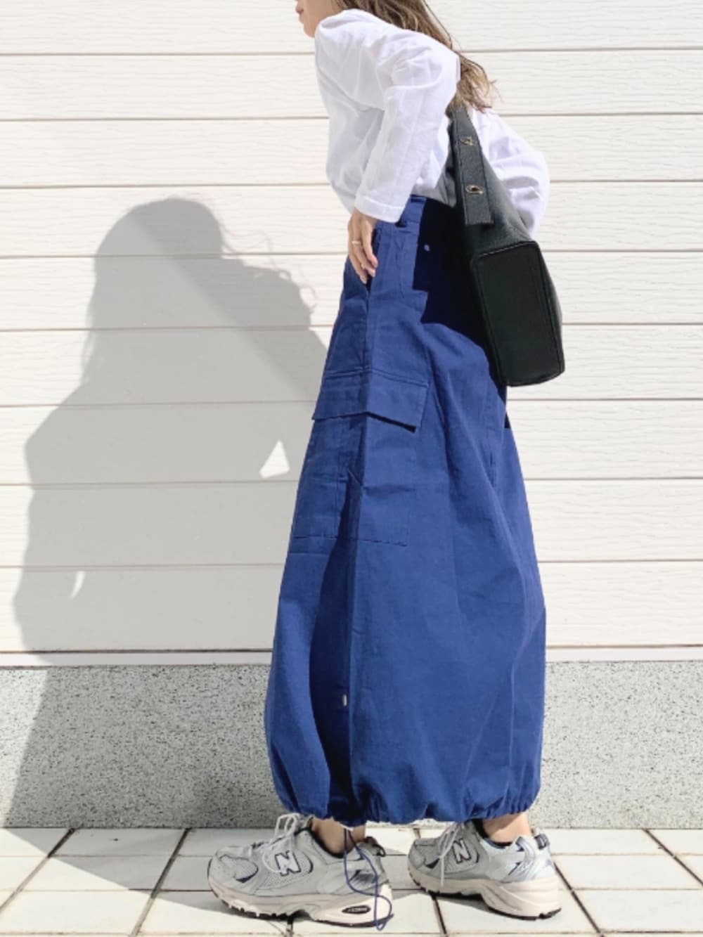 ホワイト系のTシャツ/カットソー、シルバー系のスニーカー、ブルー系のスカートを着用したレディースの春コーディネートの3枚目の写真