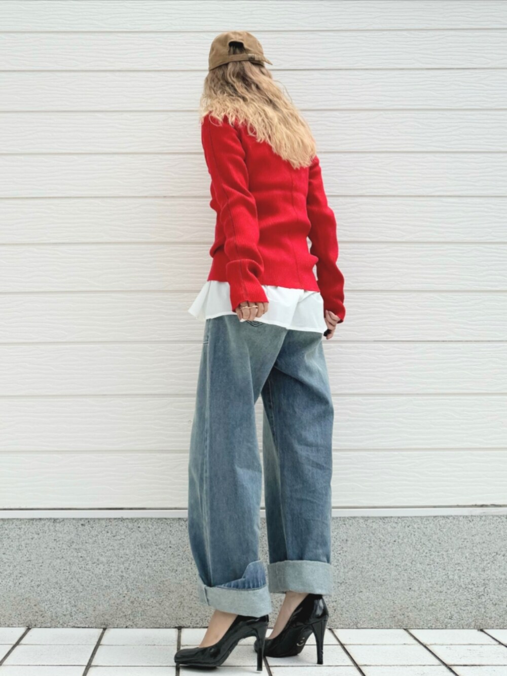 レッド系のニット/セーター、ブルー系のデニムパンツ、ホワイト系のTシャツ/カットソーを着用したレディースの秋コーディネートの3枚目の写真