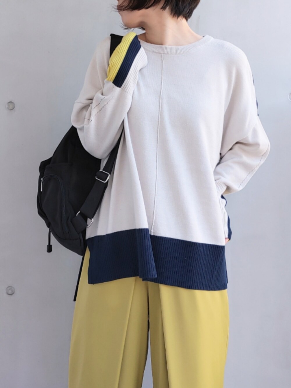 ブラック系のバックパック/リュック、グリーン系のスラックス、ベージュ系のニット/セーターを着用したレディースの冬コーディネートの4枚目の写真