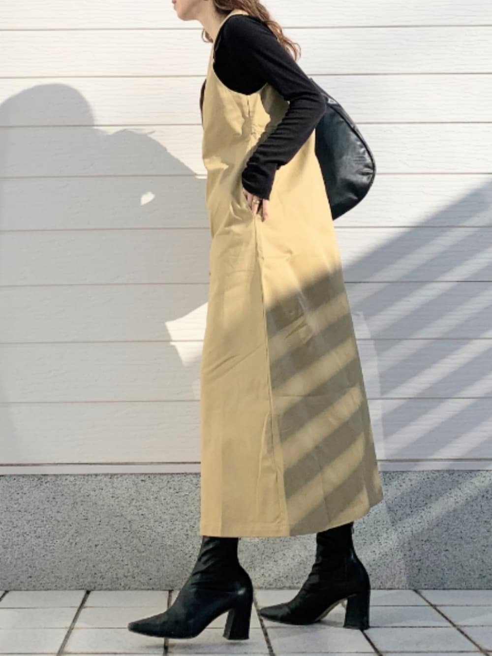 ベージュ系のジャンパースカート、ブラック系のトートバッグを着用したレディースの冬コーディネートの2枚目の写真