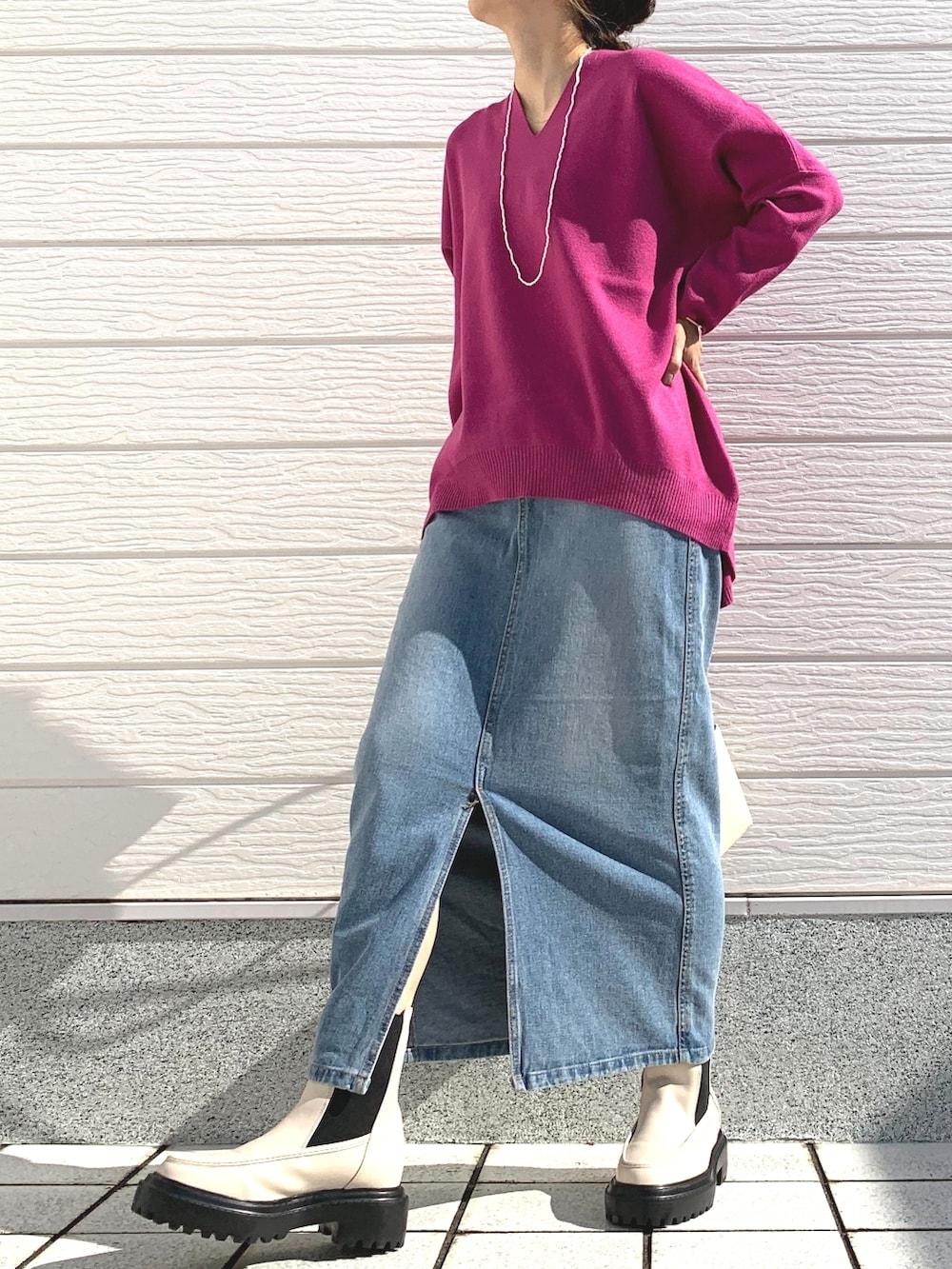 ブルー系のデニムスカート、ホワイト系のショルダーバッグ、ピンク系のニット/セーターを着用したレディースの秋コーディネートの2枚目の写真