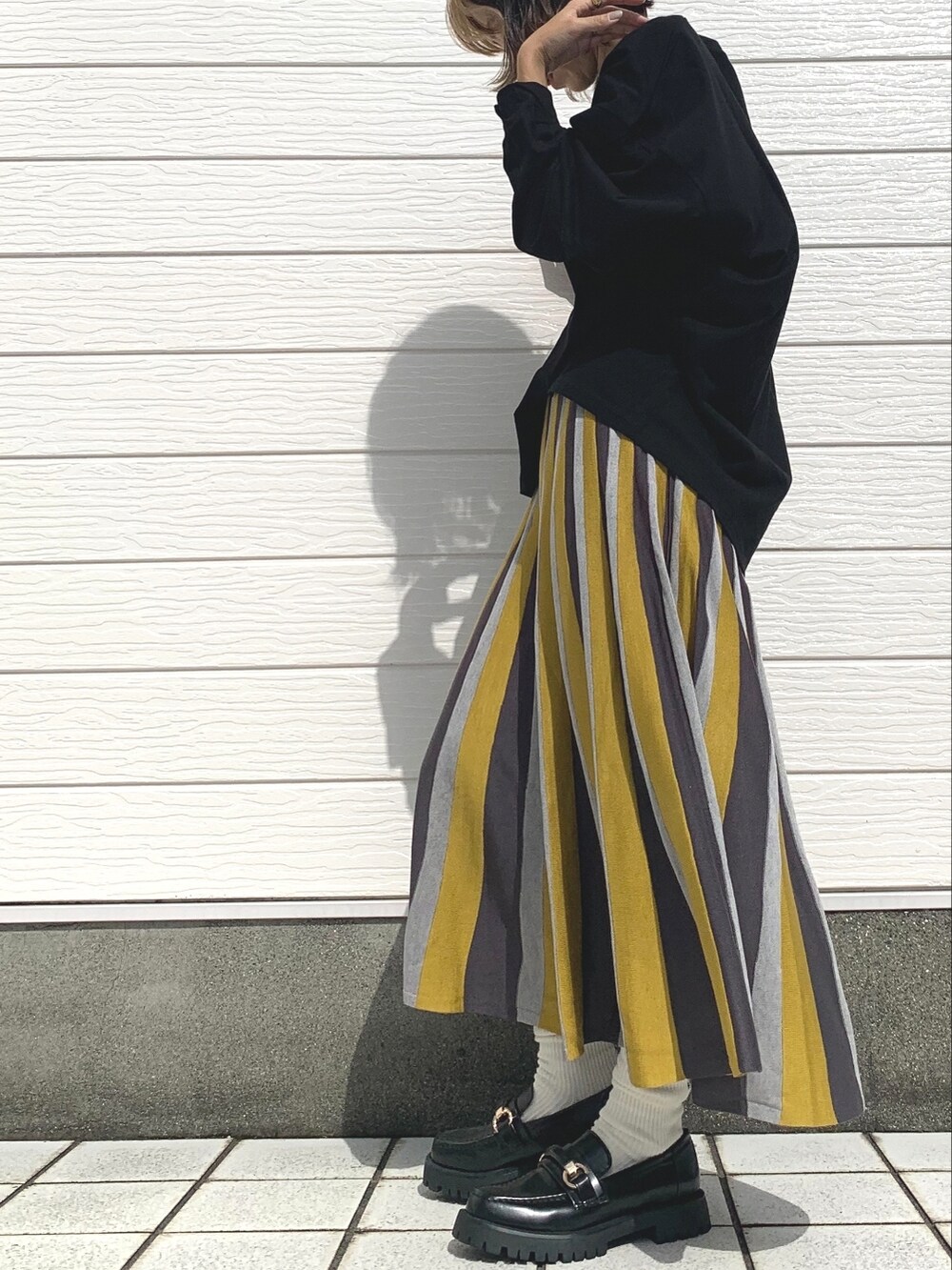 ブラック系のTシャツ/カットソー、ブラック系のローファー、イエロー系のスカートを着用したレディースの秋コーディネートの2枚目の写真