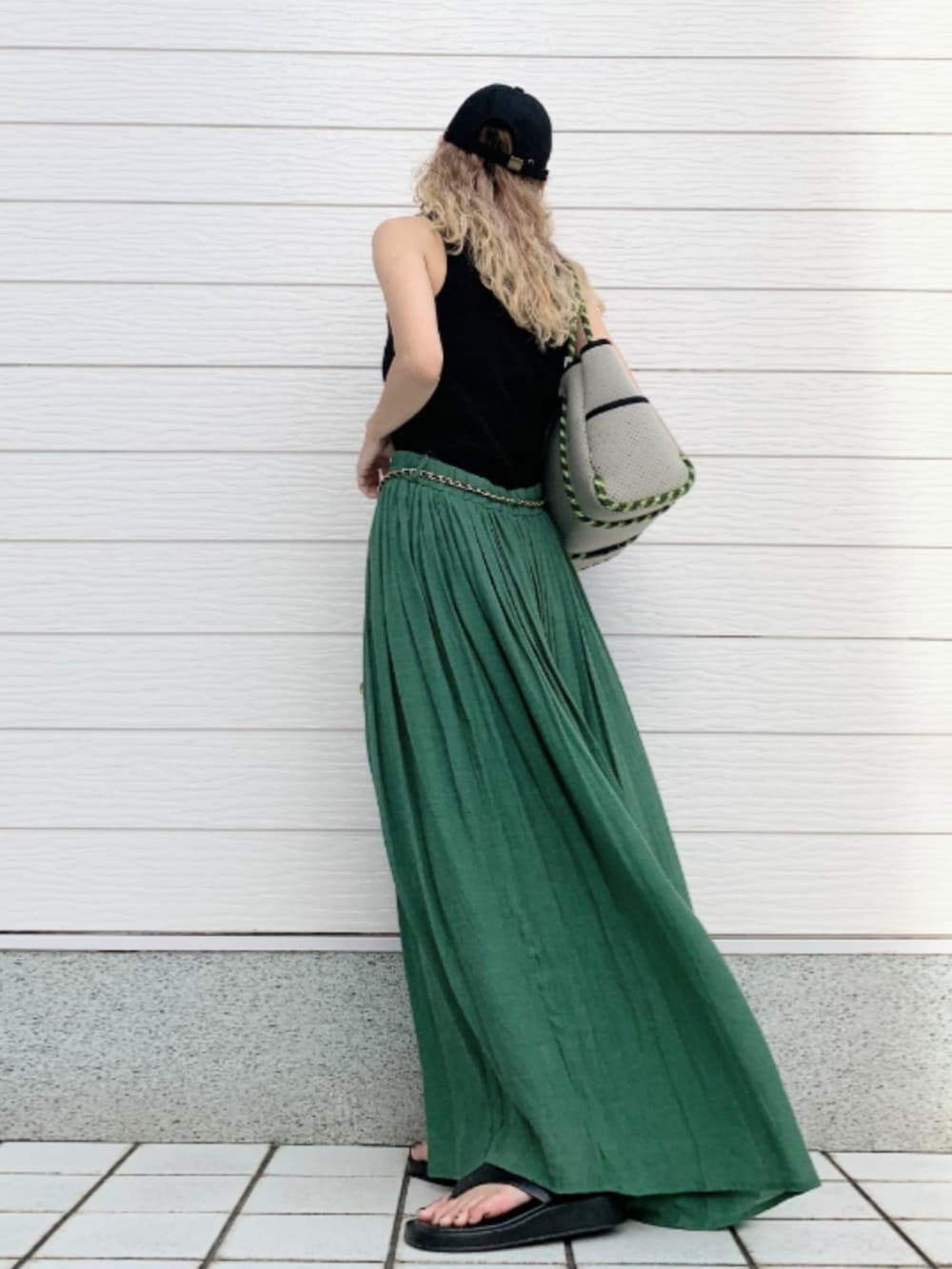 グレー系のトートバッグ、ブラック系のタンクトップ、グリーン系のスカートを着用したレディースの夏コーディネートの3枚目の写真