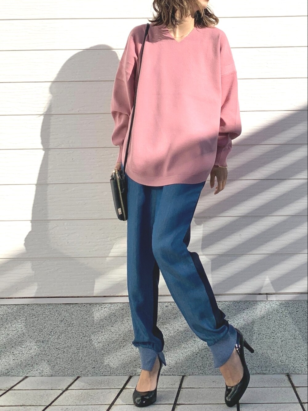 ブルー系のデニムパンツ、ブラック系のショルダーバッグ、ピンク系のニット/セーターを着用したレディースの冬コーディネートの2枚目の写真