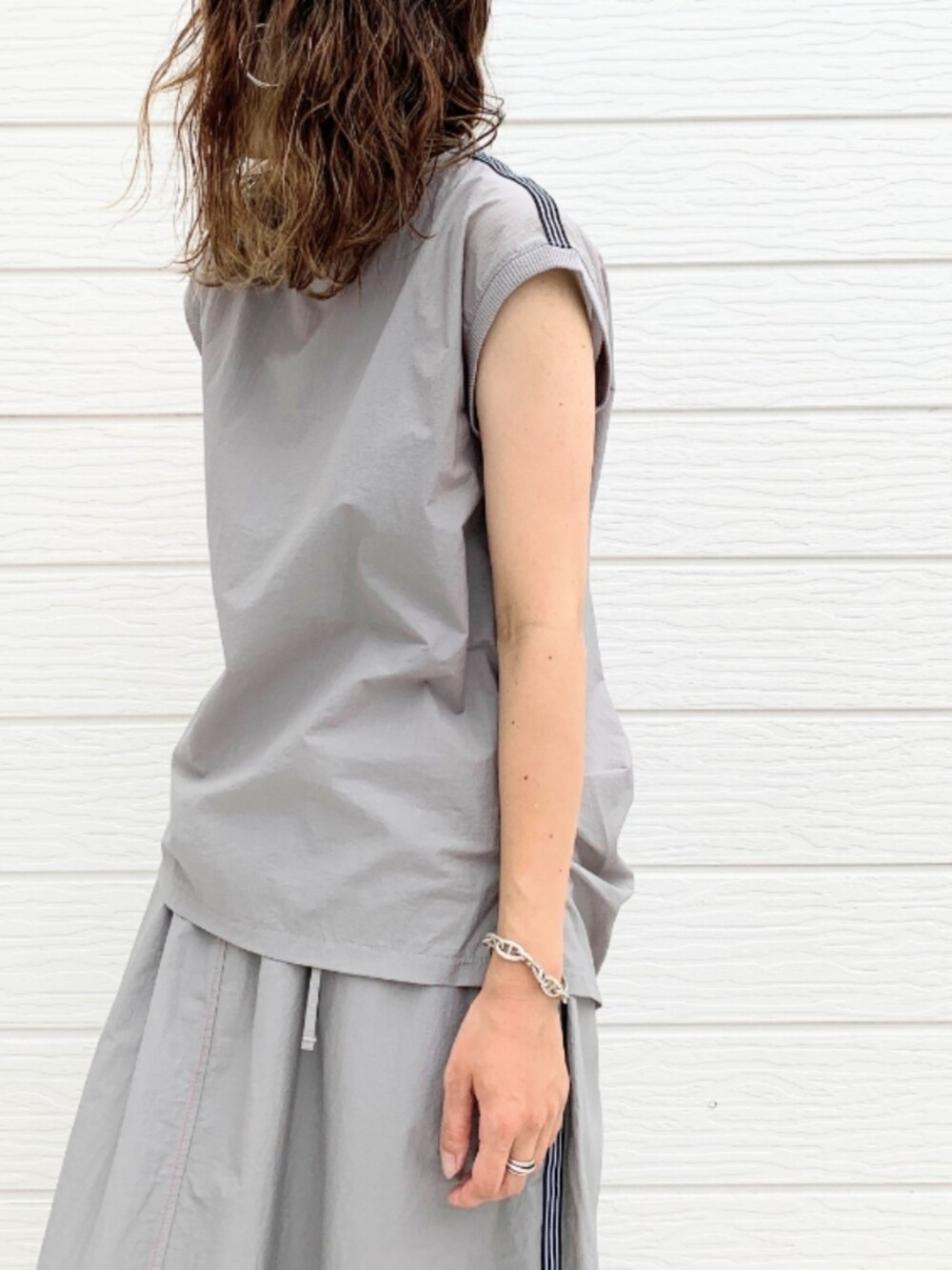 ブルー系のハンドバッグ、グレー系のTシャツ/カットソー、グレー系のスカートを着用したレディースの夏コーディネートの4枚目の写真