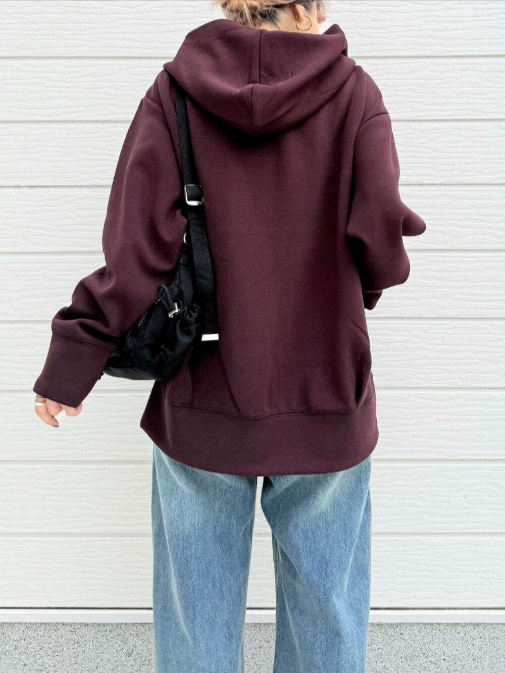 ブルー系のデニムパンツ、ブラウン系のブーツ、ブラック系のショルダーバッグを着用したレディースの秋コーディネートの5枚目の写真