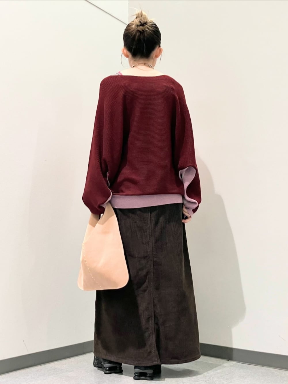 レッド系のニット/セーター、ブラウン系のスカート、ベージュ系のトートバッグを着用したレディースの秋コーディネートの4枚目の写真