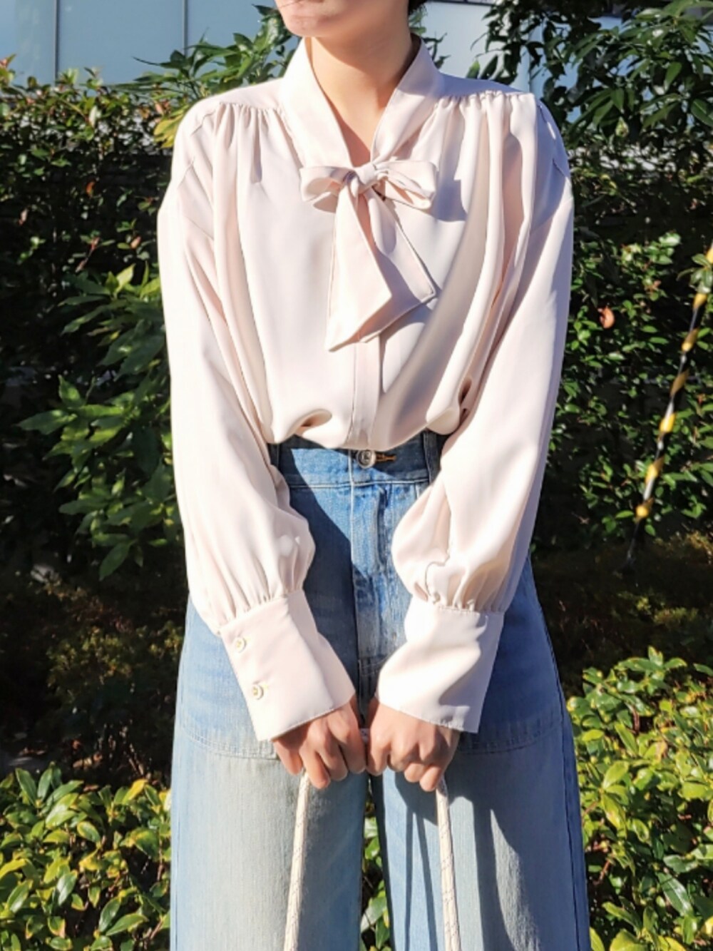 ブルー系のデニムパンツ、ブルー系のトートバッグ、ベージュ系のニット/セーターを着用したレディースの冬コーディネートの4枚目の写真