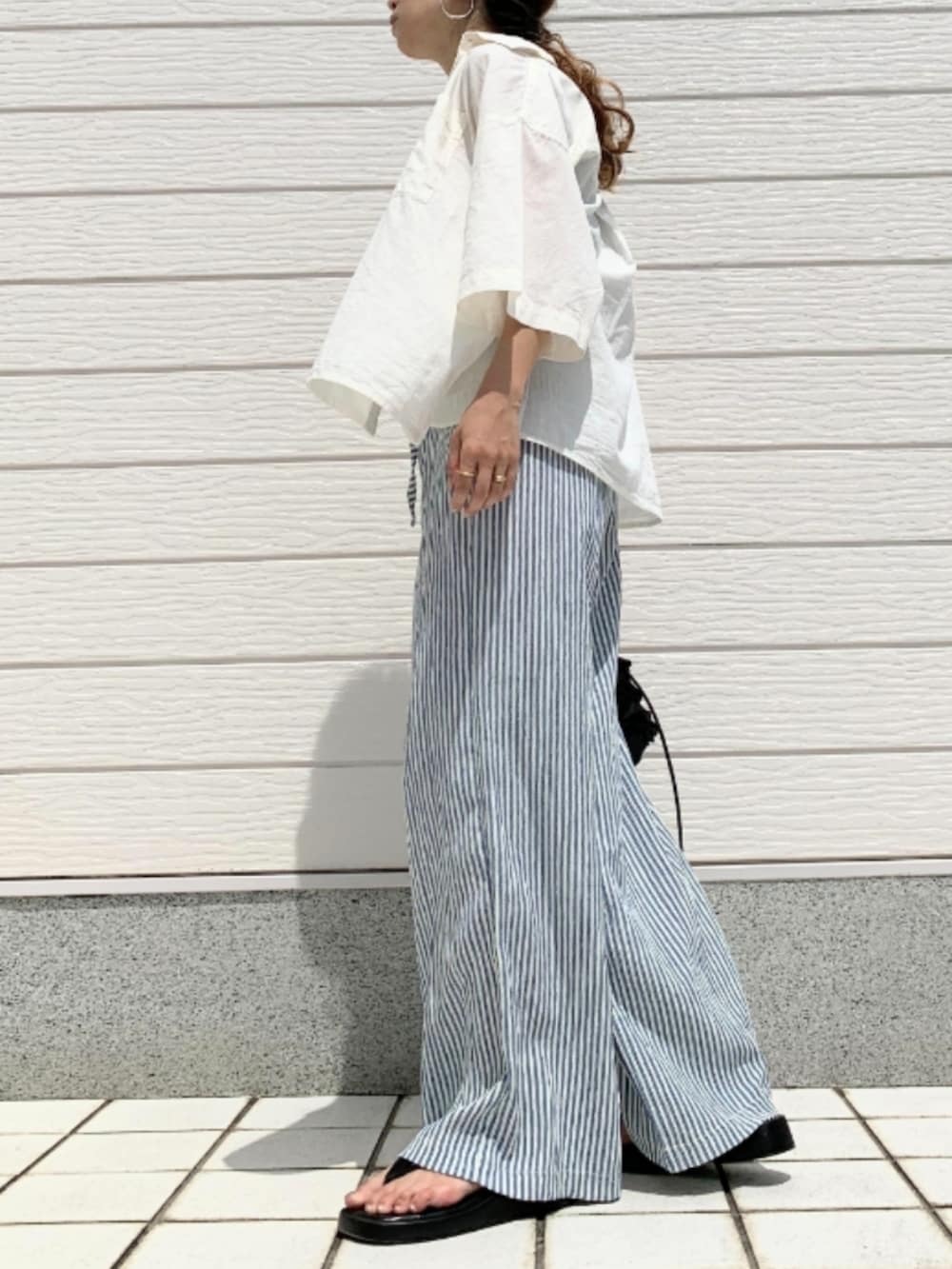 ブラック系のクラッチバッグ、ブラック系のタンクトップ、ホワイト系のシャツ/ブラウスを着用したレディースの夏コーディネートの2枚目の写真