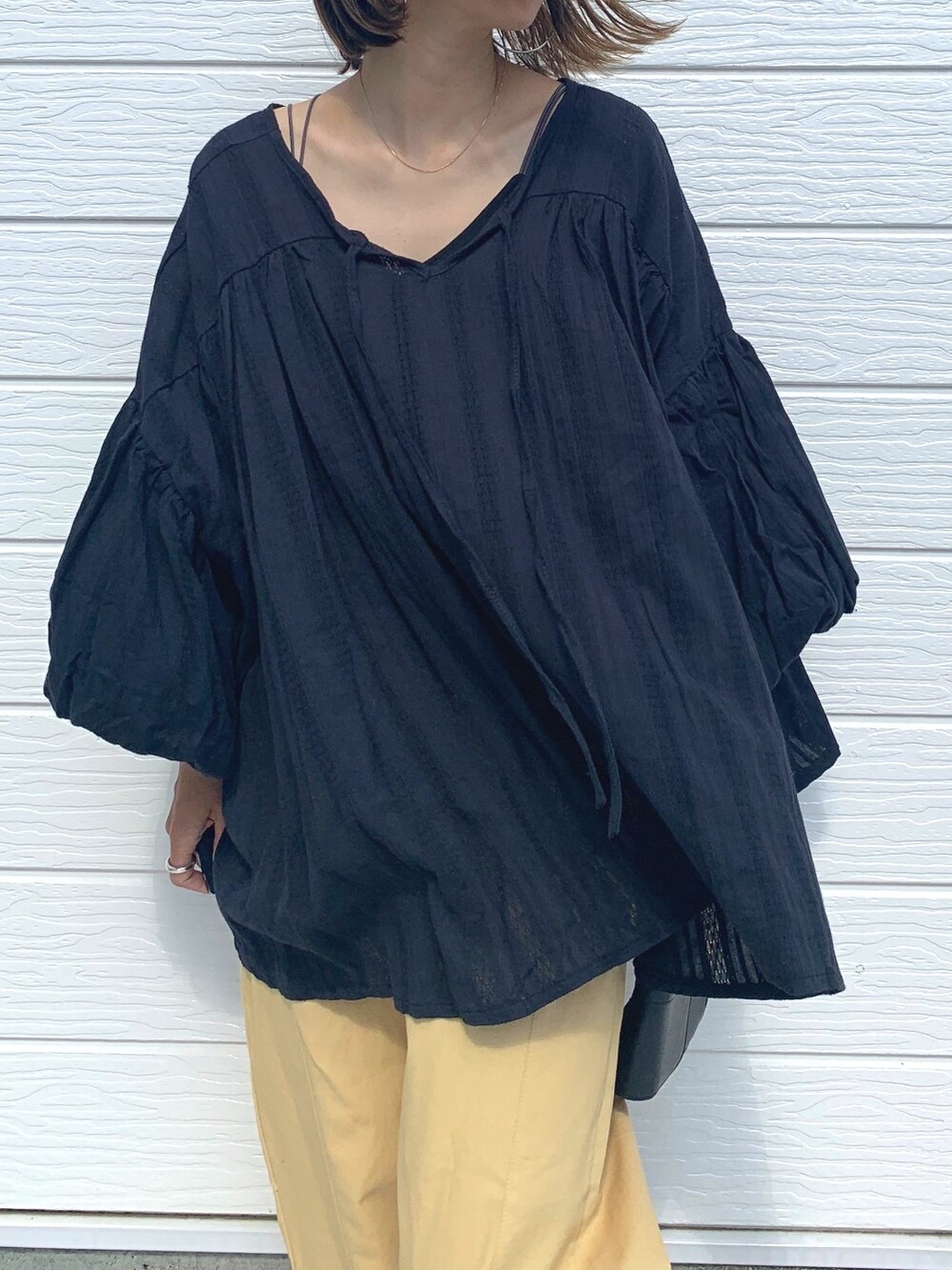 ベージュ系のチノパンツ、ブラック系のシャツ/ブラウスを着用したレディースの夏コーディネートの2枚目の写真