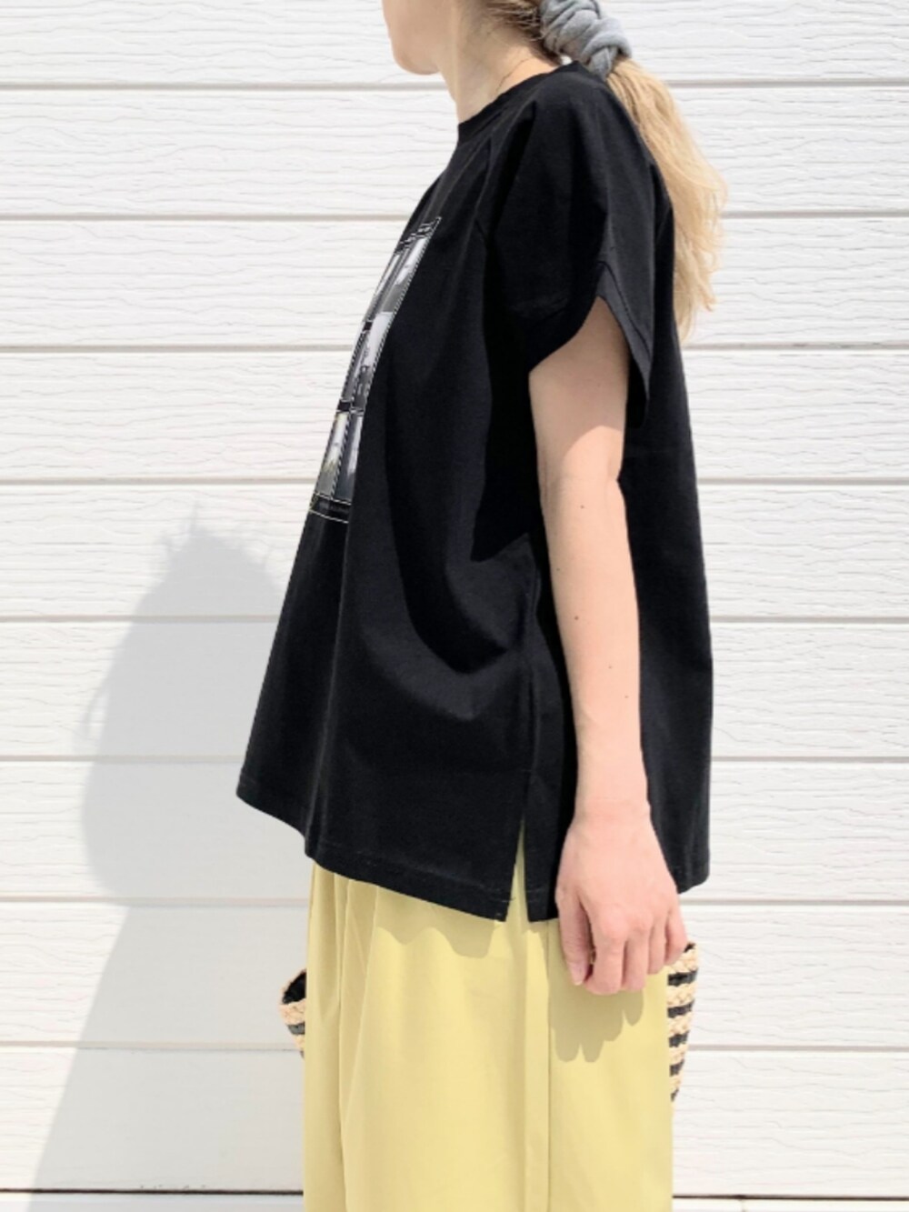 ブラック系のかごバッグ、イエロー系のその他パンツ、ブラック系のTシャツ/カットソーを着用したレディースの春コーディネートの5枚目の写真