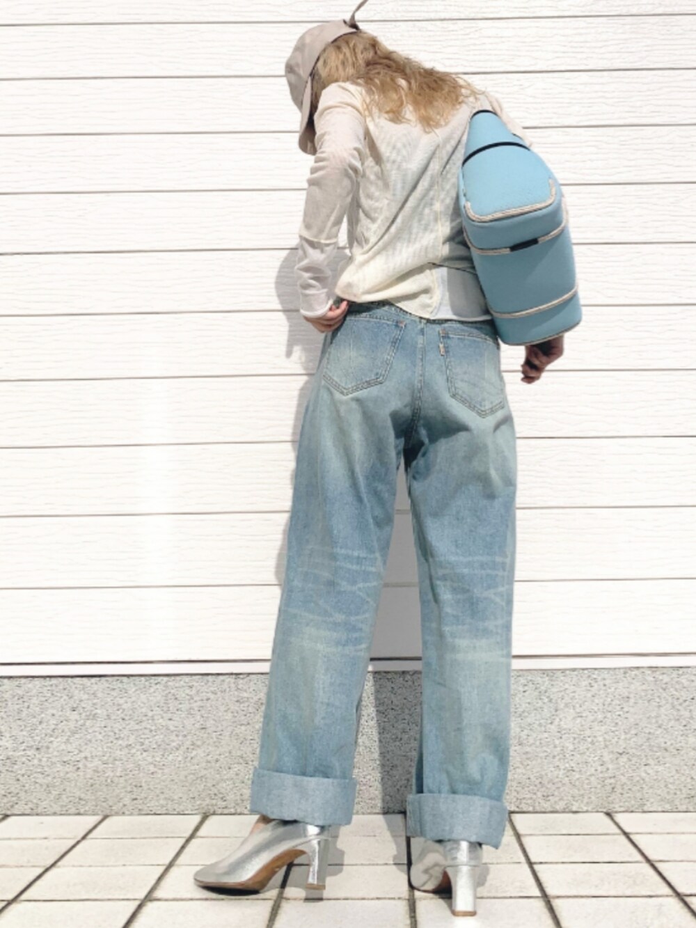 ブルー系のデニムパンツ、ブルー系のトートバッグ、ベージュ系のTシャツ/カットソーを着用したレディースの春コーディネートの2枚目の写真