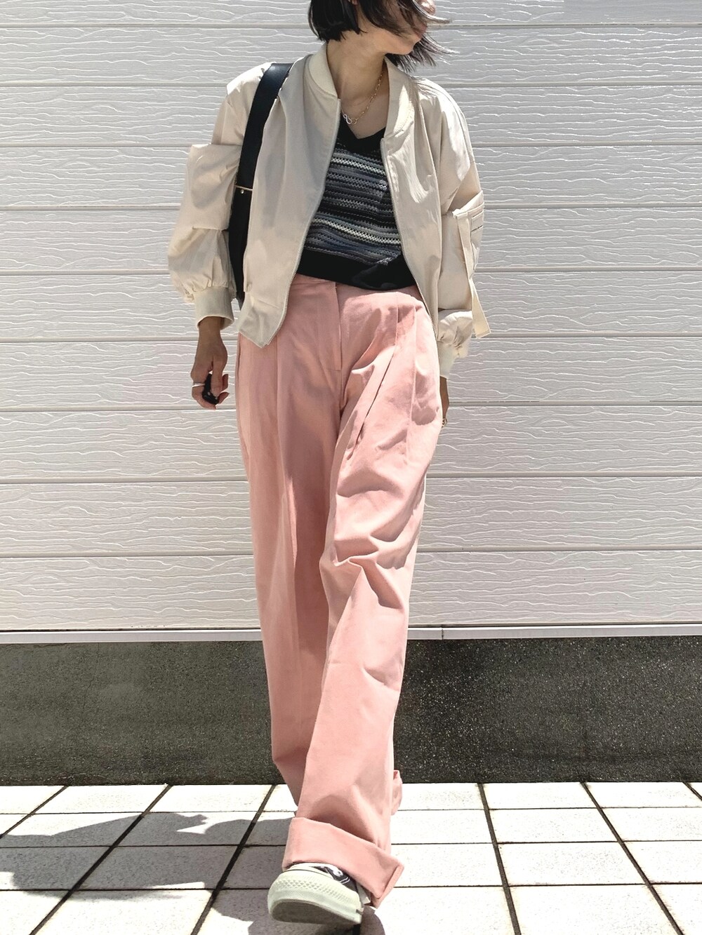 ベージュ系のブルゾン、ブラック系のショルダーバッグ、ブラック系のスニーカーを着用したレディースの夏コーディネートの2枚目の写真