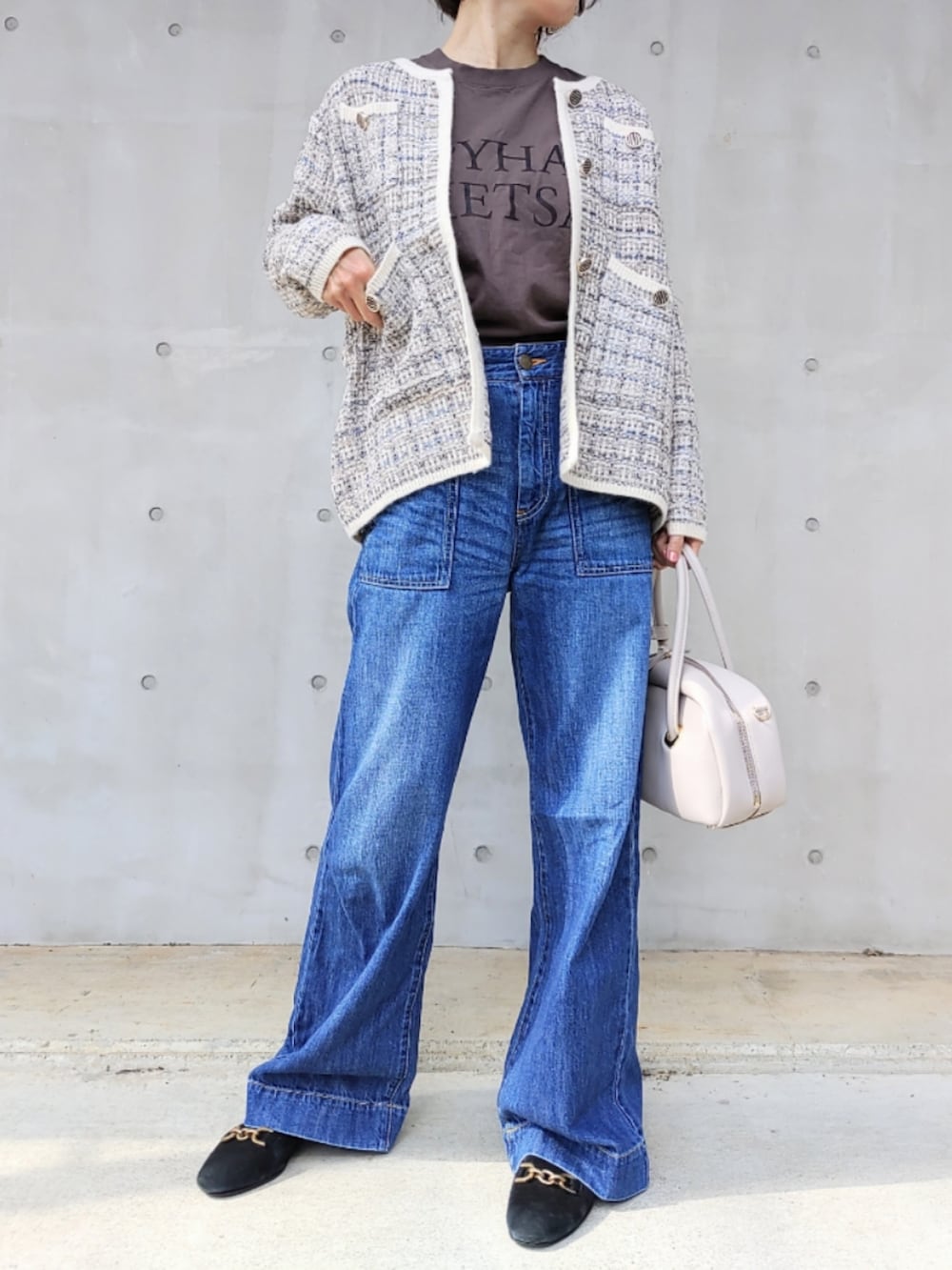ホワイト系のボストンバッグ、ブルー系のデニムパンツ、ホワイト系のカーディガン/ボレロを着用したレディースの秋コーディネートの3枚目の写真
