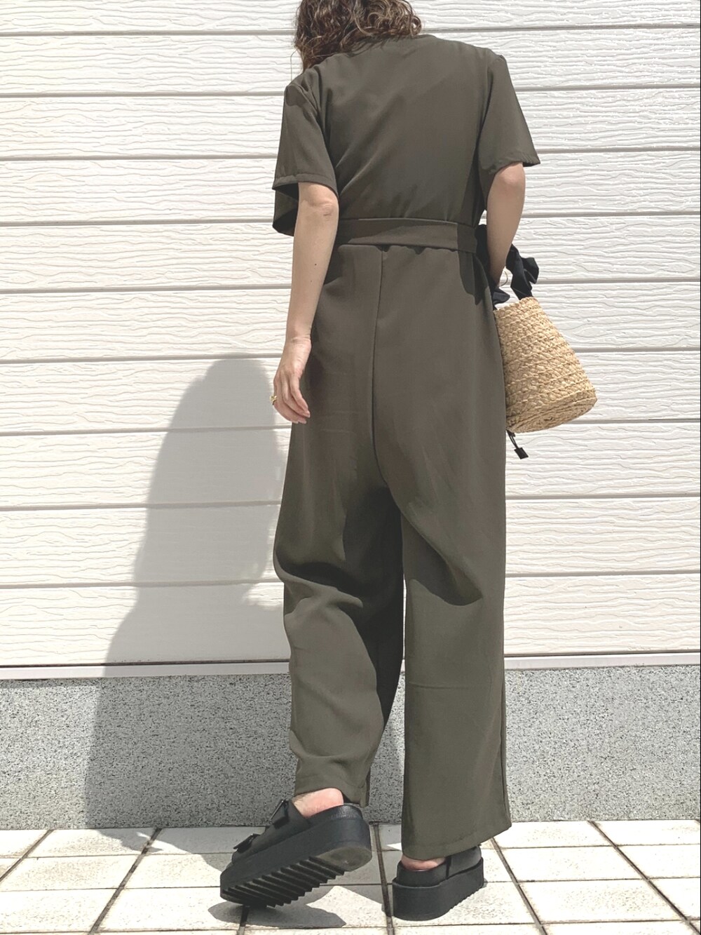 ブラック系のかごバッグ、グリーン系のつなぎ/オールインワン、ブラック系のサンダルを着用したレディースの春コーディネートの3枚目の写真