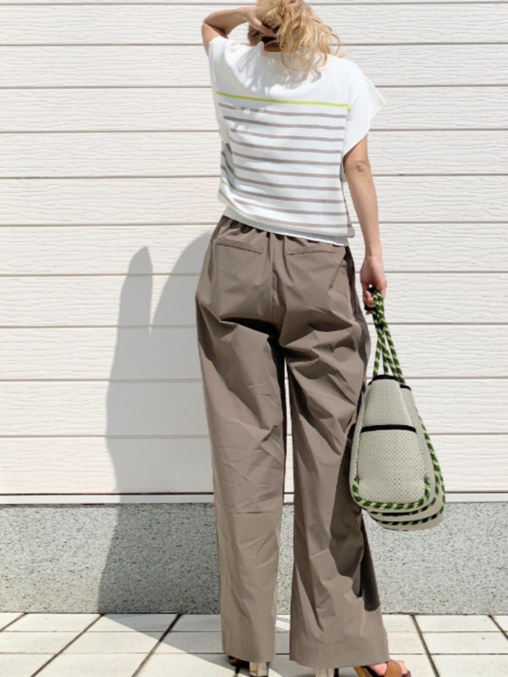 グレー系のその他パンツ、グレー系のトートバッグ、ホワイト系のニット/セーターを着用したレディースの春コーディネートの2枚目の写真