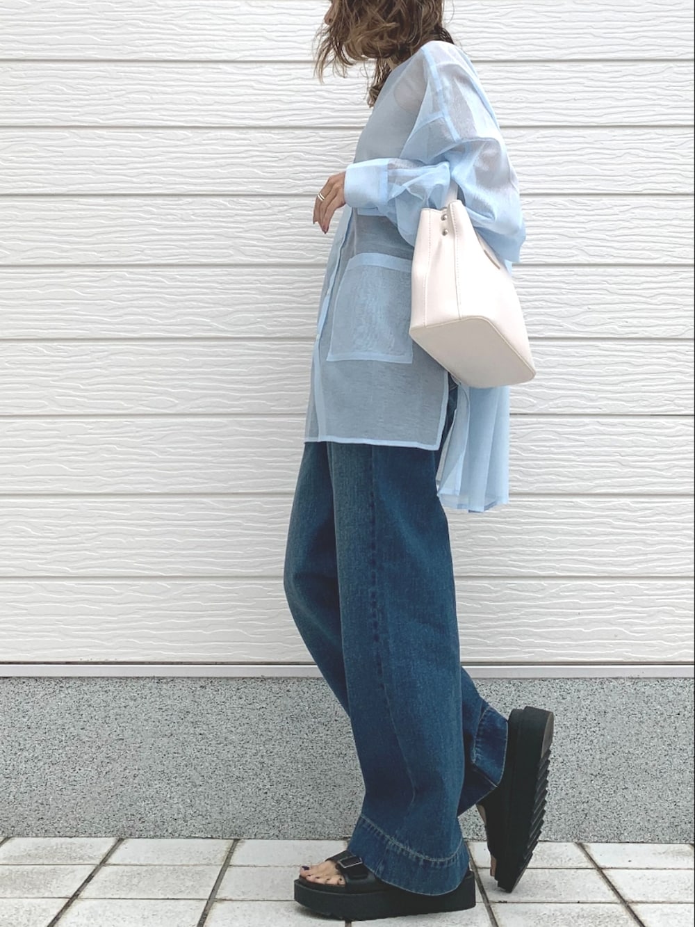 ブルー系のデニムパンツ、ブラック系のサンダル、ホワイト系のハンドバッグを着用したレディースの春コーディネートの3枚目の写真