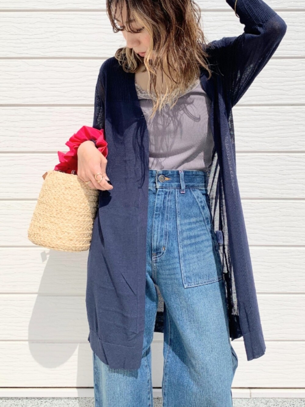 ブラック系のサンダル、ブルー系のデニムパンツ、ピンク系のかごバッグを着用したレディースの春コーディネートの3枚目の写真