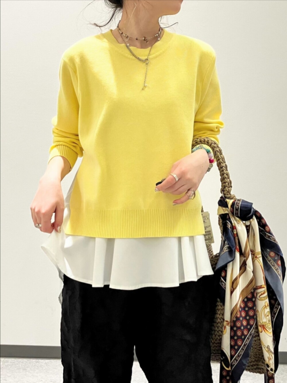 ブラック系のその他パンツ、ベージュ系のトートバッグ、イエロー系のニット/セーターを着用したレディースの春コーディネートの3枚目の写真