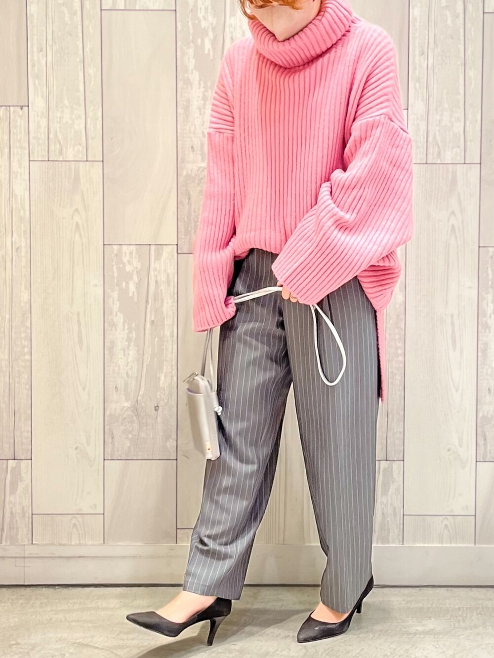 グレー系のその他パンツ、シルバー系のショルダーバッグ、ピンク系のニット/セーターを着用したレディースの冬コーディネートの2枚目の写真