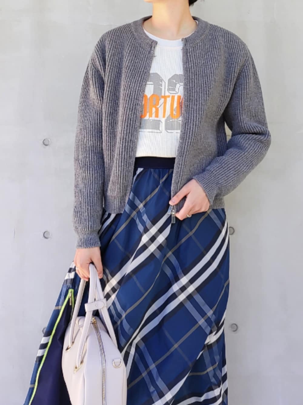 ホワイト系のボストンバッグ、ブルー系のスカート、ホワイト系のスニーカーを着用したレディースの冬コーディネートの3枚目の写真