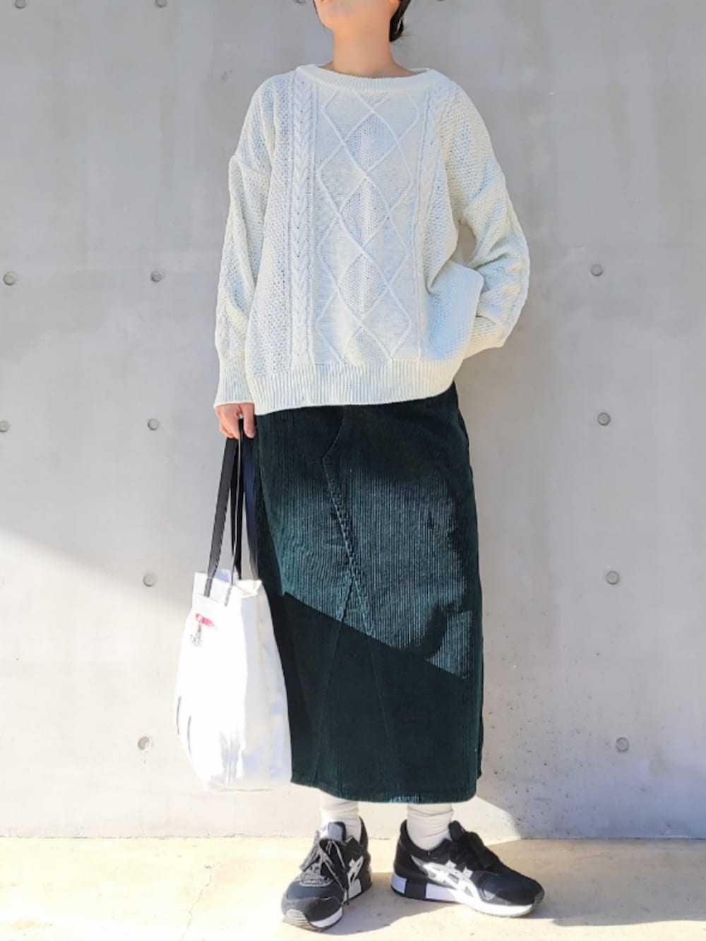 ホワイト系のトートバッグ、ブラック系のスニーカー、ホワイト系のニット/セーターを着用したレディースの冬コーディネートの2枚目の写真