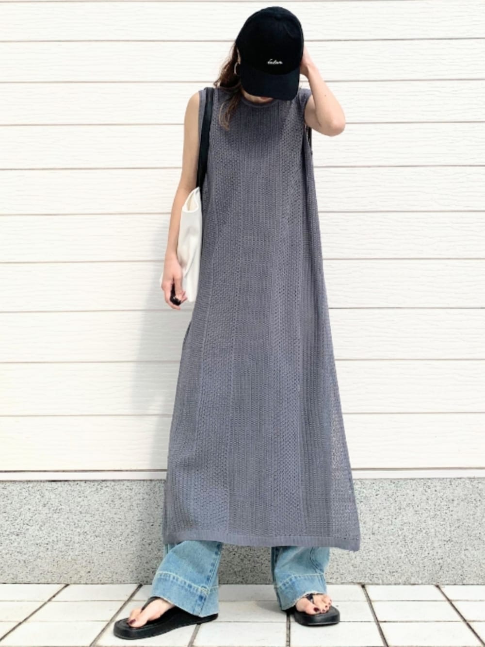 ホワイト系のトートバッグ、ブルー系のデニムパンツ、グレー系のワンピースを着用したレディースの春コーディネートの3枚目の写真