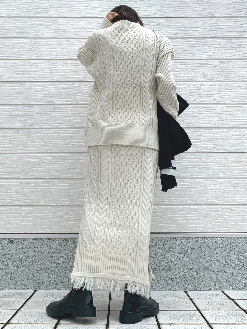 シルバー系のショルダーバッグ、ホワイト系のスカート、ホワイト系のニット/セーターを着用したレディースの冬コーディネートの3枚目の写真