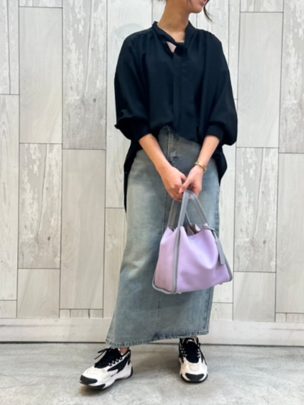 パープル系のトートバッグ、ブルー系のデニムスカート、ブラック系のシャツ/ブラウスを着用したレディースの冬コーディネートの2枚目の写真