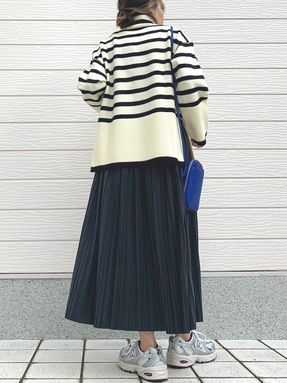 シルバー系のスニーカー、ブルー系のショルダーバッグ、ホワイト系のニット/セーターを着用したレディースの秋コーディネートの3枚目の写真