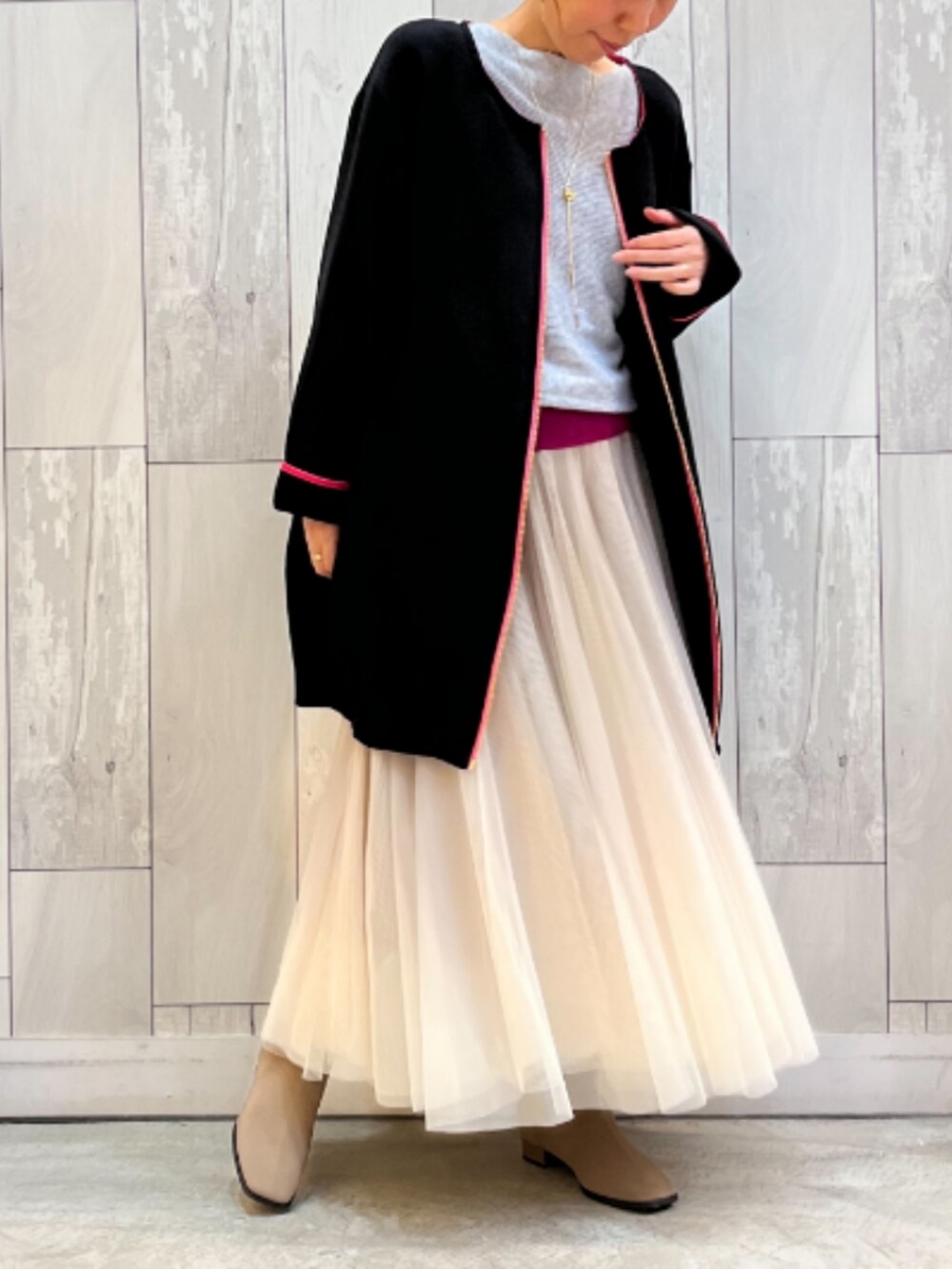 ゴールド系のスカート、ベージュ系のブーツ、ブラック系のニット/セーターを着用したレディースの秋コーディネートの2枚目の写真