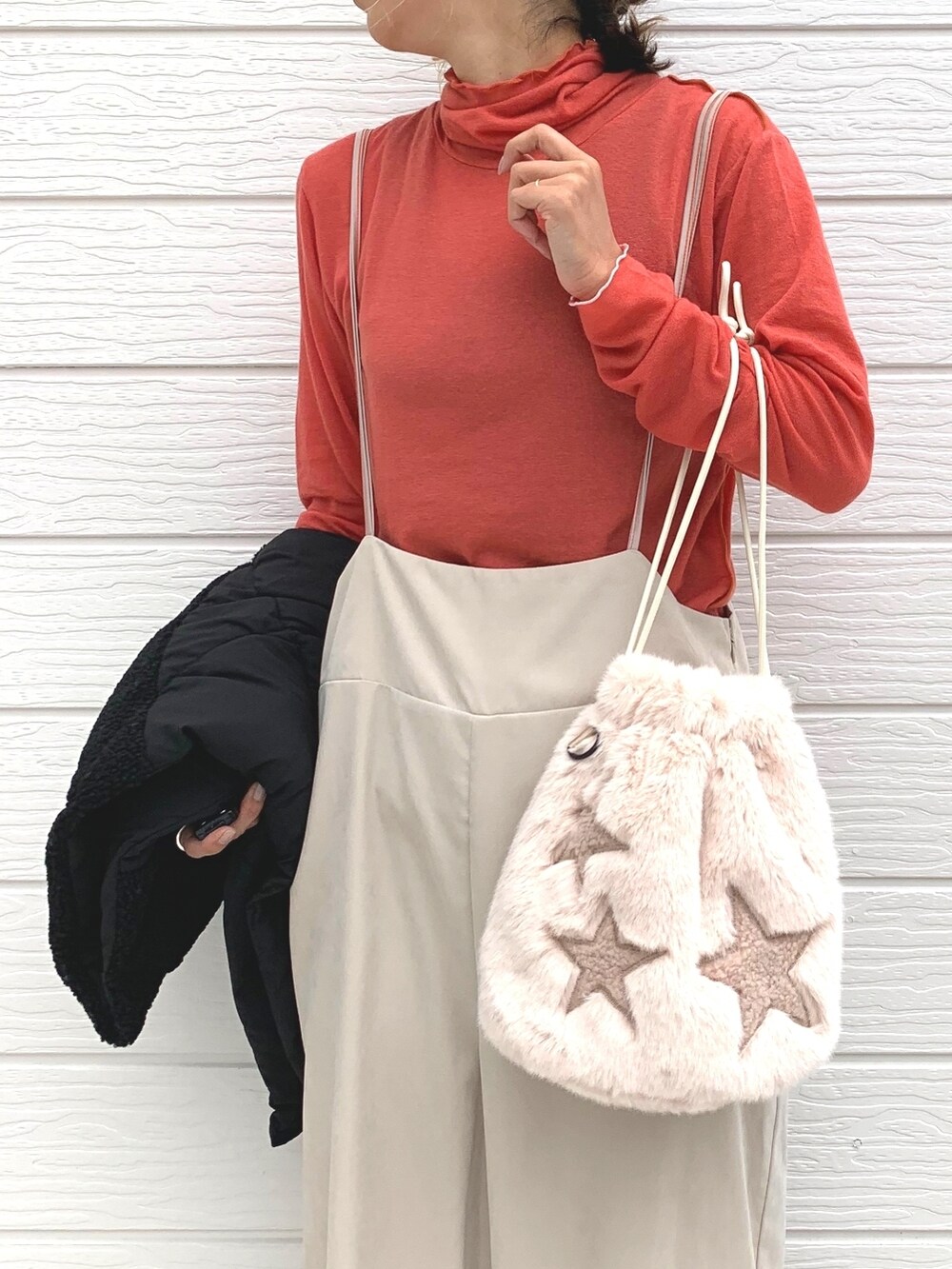 ベージュ系のショルダーバッグ、オレンジ系のTシャツ/カットソー、ベージュ系のサロペット/オーバーオールを着用したレディースの秋コーディネートの3枚目の写真