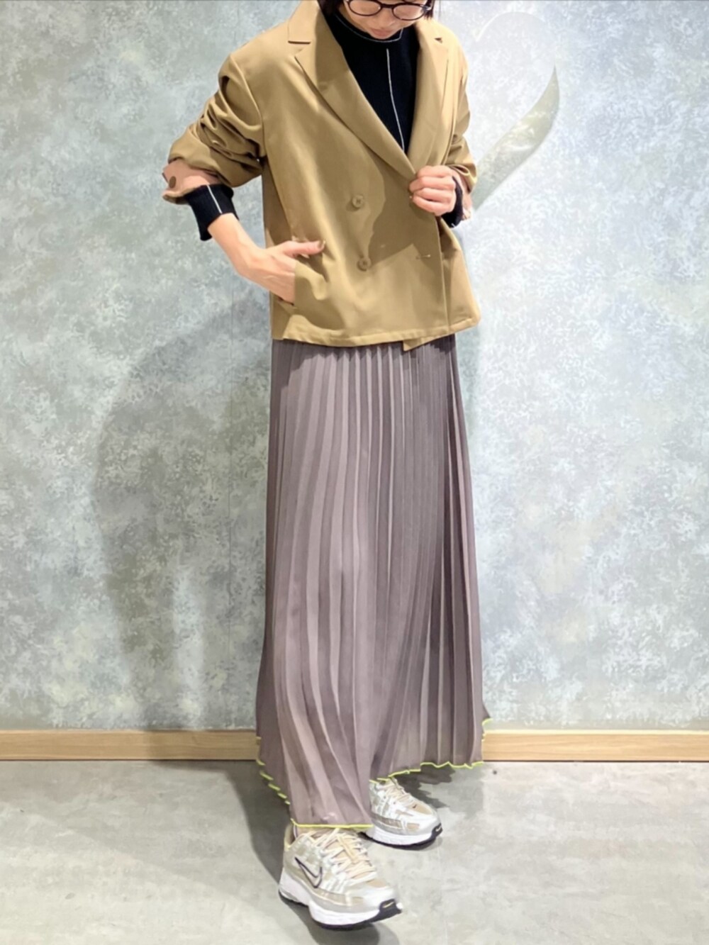 グリーン系のスカート、ブラウン系のテーラードジャケット、ブラック系のニット/セーターを着用したレディースの秋コーディネートの2枚目の写真